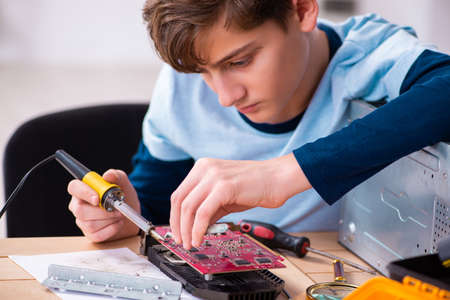 Boy reparing computers at workshopの写真素材