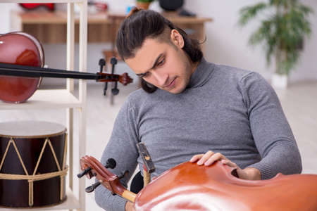 Young male repairman repairing celloの写真素材