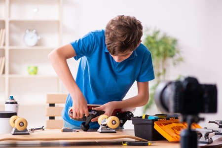 Boy repairing skateboard and recording video for his blogの写真素材