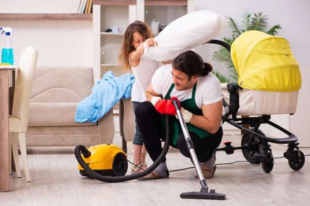 Young male contractor cleaning the house with his small daughterの写真素材