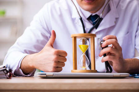 Young male doctor in time management concept