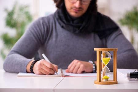 Young male writer in time management concept