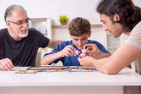 Three generations of family playing jigsaw puzzle gameの写真素材
