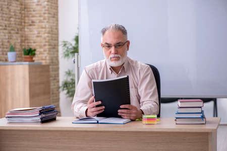 Old male teacher sitting in the classroom