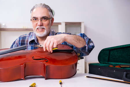Senior male repairman repairing musical instruments at home