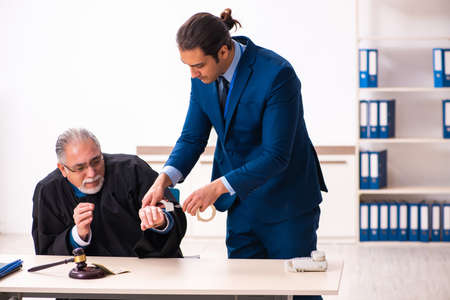 Police inspector arresting old judge in courtの写真素材