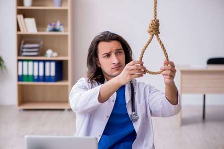 Young male doctor committing suicide in the hospitalの写真素材