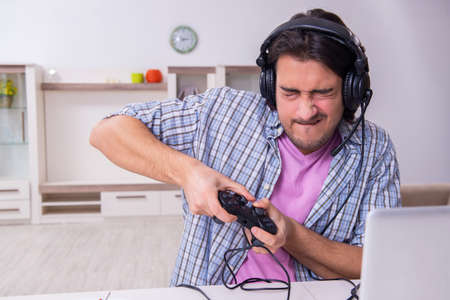 Young male student playing computer games at home