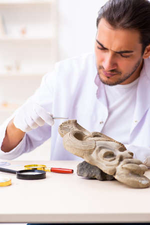 Young male archaeologist studying ancient african stonemaskの写真素材
