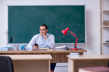 Young male teacher in front of green boardの写真素材