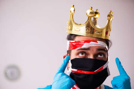 Young man with crown on head at homeの写真素材