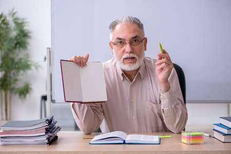 Old male teacher sitting in the classroom