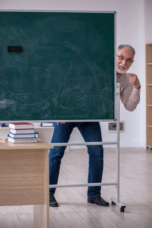 Old male teacher sitting in the classroomの写真素材