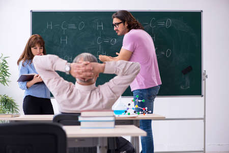 Old chemist teacher and two students in the classroomの写真素材