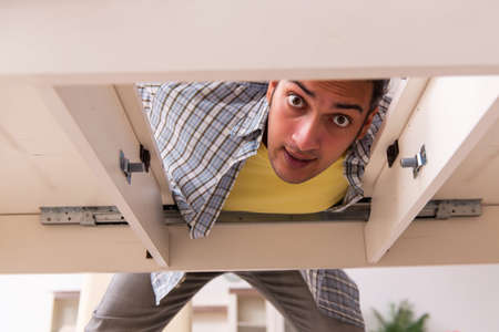 Young male carpenter repairing furniture at homeの写真素材