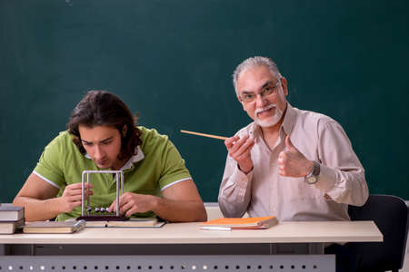 Old professor physicist and young student in the classroomの写真素材