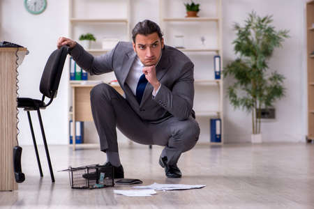Young male employee and mousetrap in the officeの写真素材