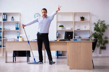 Young male employee cleaning office during pandemicの写真素材
