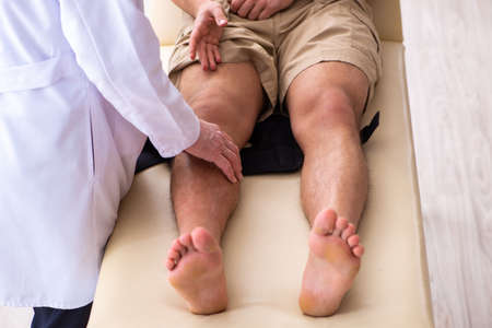 Experienced doctor traumatologist examining young male patientの写真素材