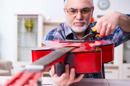 Senior male repairman repairing musical instruments at homeの写真素材
