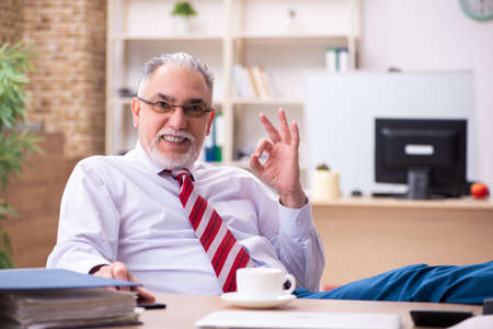 Old male employee enjoying coffee during coffee breakの写真素材