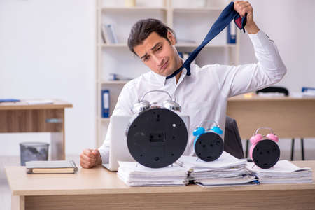 Young male employee afraid of missing deadline at workplaceの写真素材