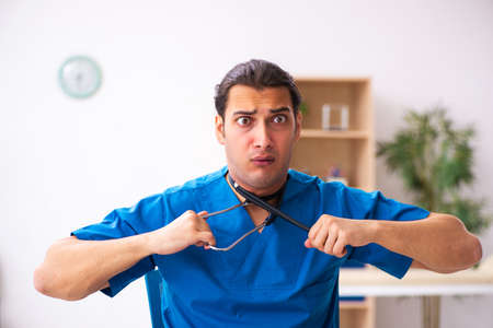 Young male doctor committing suicide at workplaceの写真素材