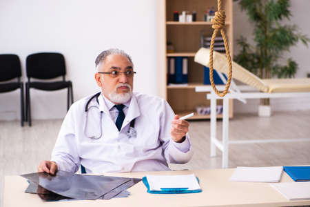 Old male doctor committing suicide at workplaceの写真素材