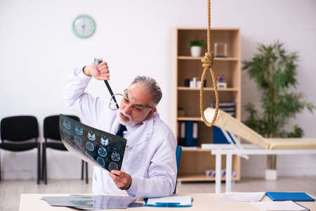 Old male doctor committing suicide at workplaceの写真素材