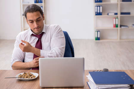 Hungry male employee eating buckwheat during breakの写真素材