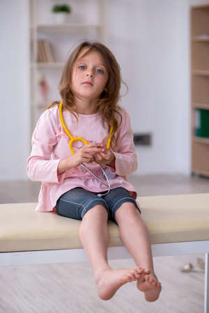 Small girl holding stethoscope waiting for doctor in the clinicの写真素材