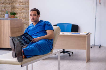 Young male doctor radiologist being unhappy after night shiftの写真素材