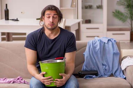 Young alcohol addicted man suffering from stomachache at homeの写真素材