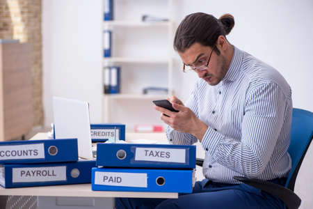 Young male bookkeeper calculating tax payments in the officeの写真素材
