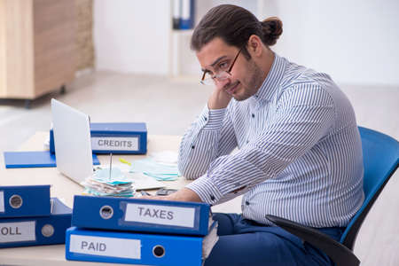 Young male bookkeeper calculating tax payments in the officeの写真素材