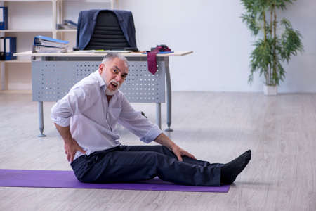 Aged male employee doing physical exercises during break