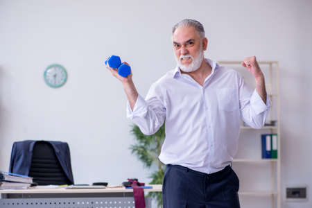 Aged male employee doing physical exercises during breakの写真素材