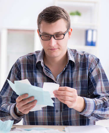Young man frustrated at his house and tax billsの写真素材