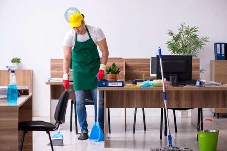 Young male contractor cleaning the officeの写真素材