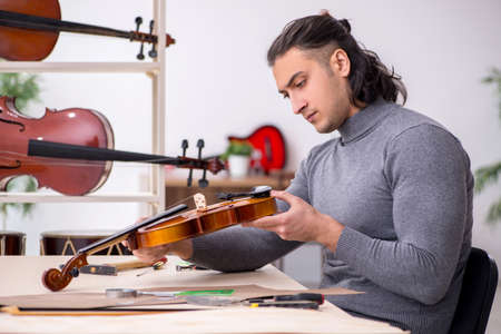 Young male repairman repairing violinの写真素材