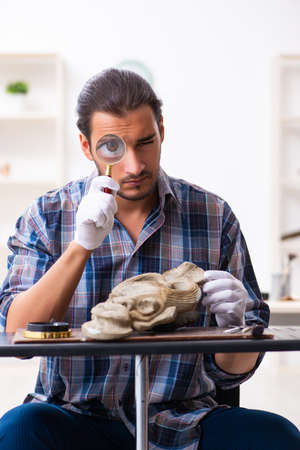 Young male archaeologist studying ancient african stonemaskの写真素材