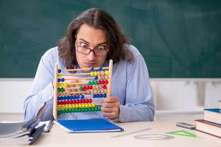 Young male teacher in front of green board