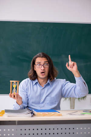 Young male teacher in front of green boardの写真素材
