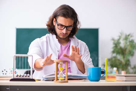 Young male physicist teacher in time management concept