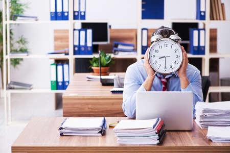 Young male employee unhappy with excessive work in time managemeの写真素材