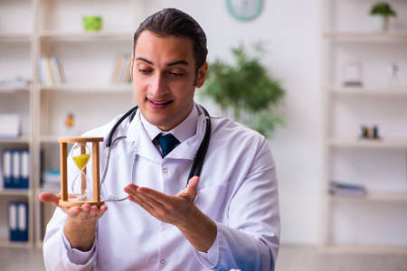 Young male doctor in time management conceptの写真素材