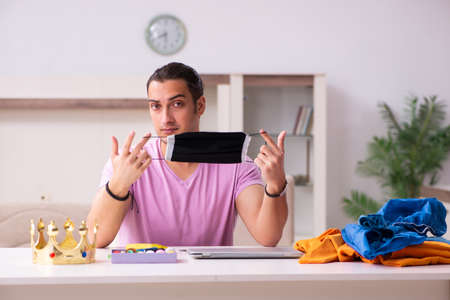 Young male tailor sewing masks at home during pandemicの写真素材