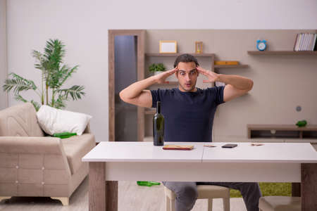 Young sick male alcoholic suffering at homeの写真素材