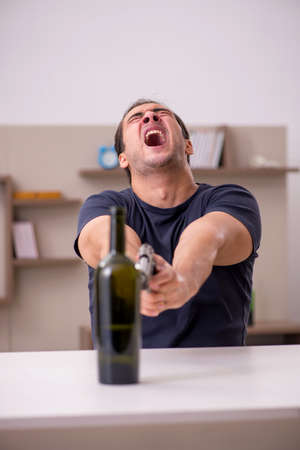 Young male alcoholic shooting gun at homeの写真素材