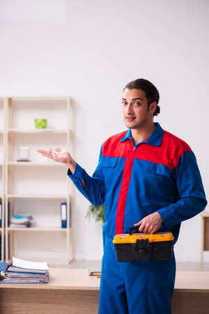 Young male contractor repairing furniture in the officeの写真素材